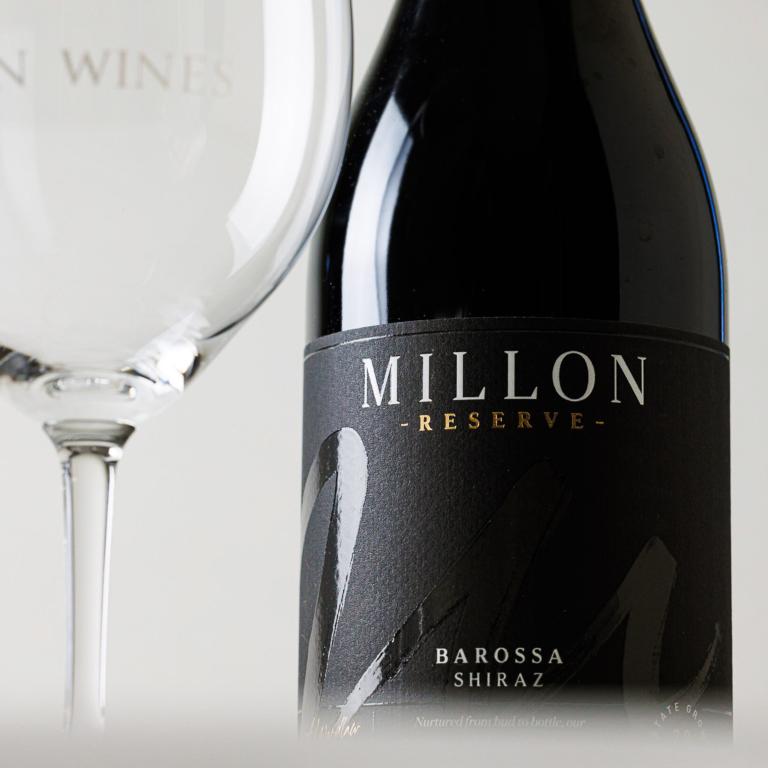 Close up shot of a bottle of Millon Wines 2020 Reserve Shiraz next to an empty  wine glass